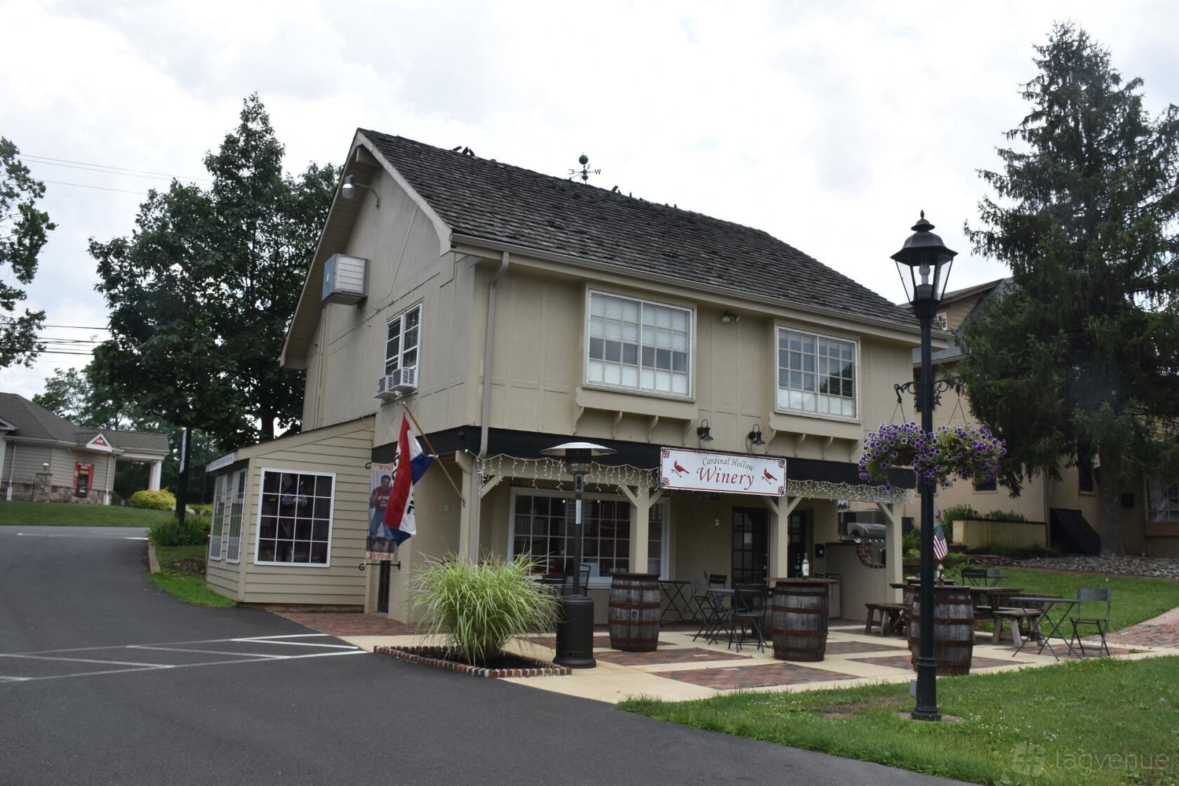 A two-story pub with a covered outdoor patio, hanging baskets, and barrel decor at Cardinal Hollow Winery.