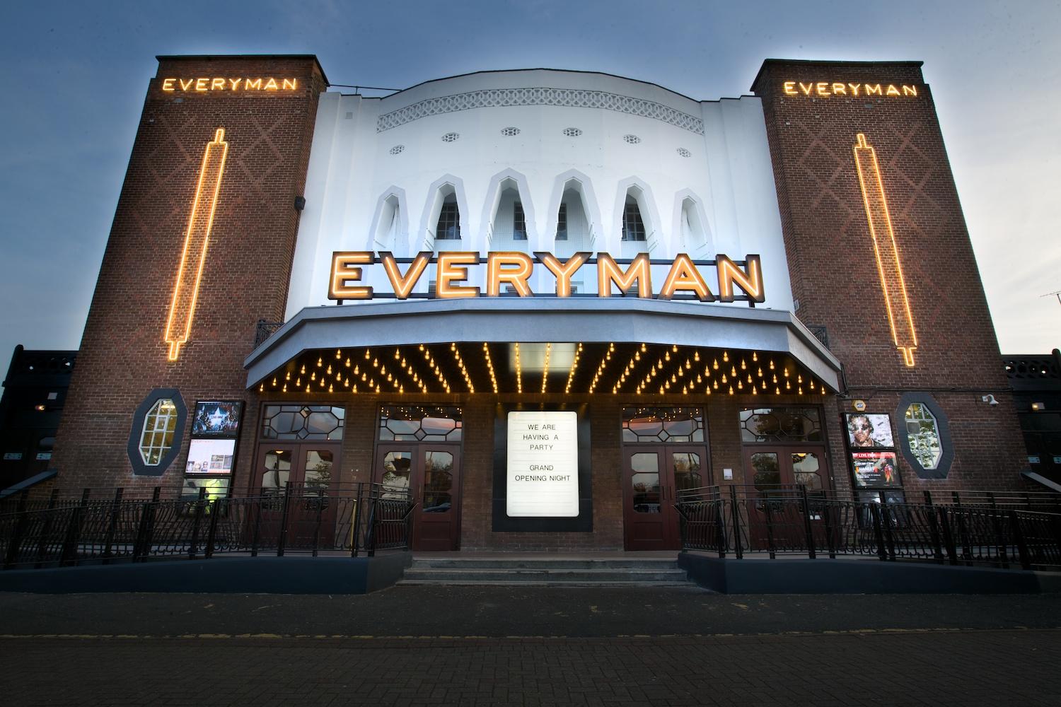 A cinema with a brick facade, marquee lights, and arched windows at Everyman Barnet.