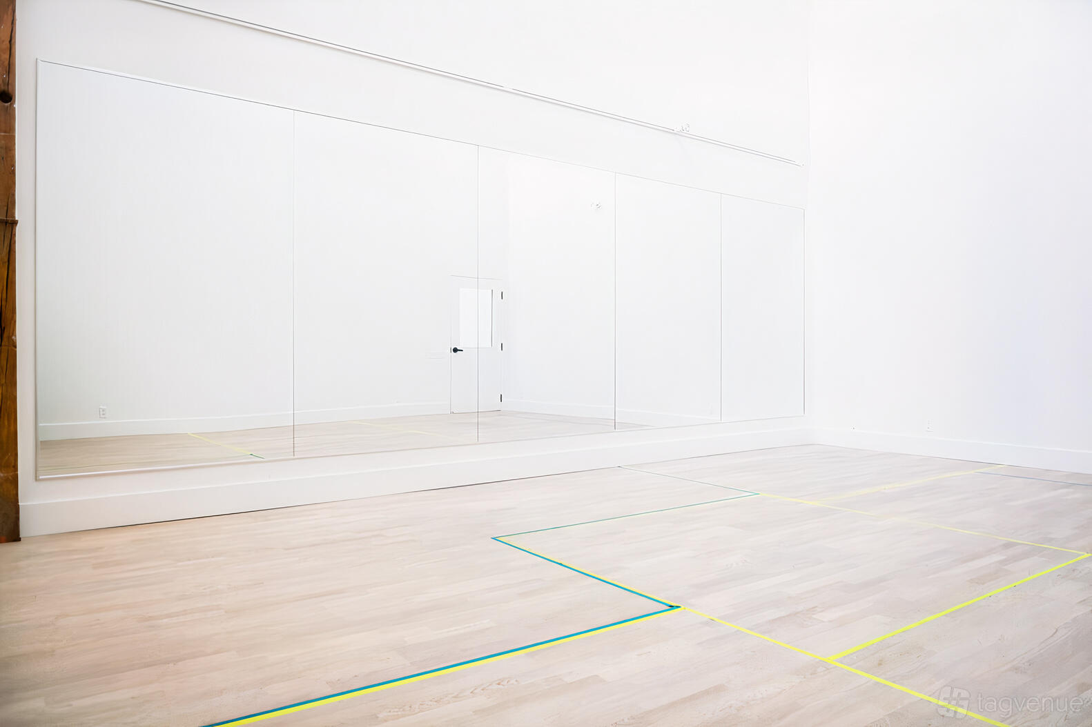 A rehearsal studio with floor-to-ceiling mirrors and light wood floors at City Dance Corps.