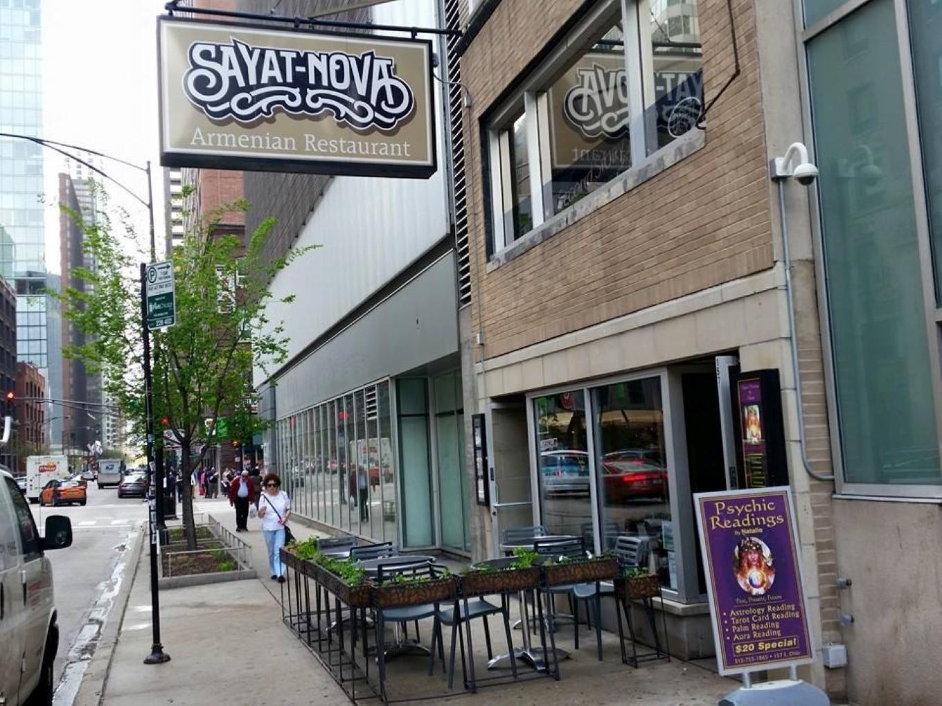 A restaurant with outdoor sidewalk seating, planter boxes, and street-facing windows at Sayat Nova Armenian Restaurant.