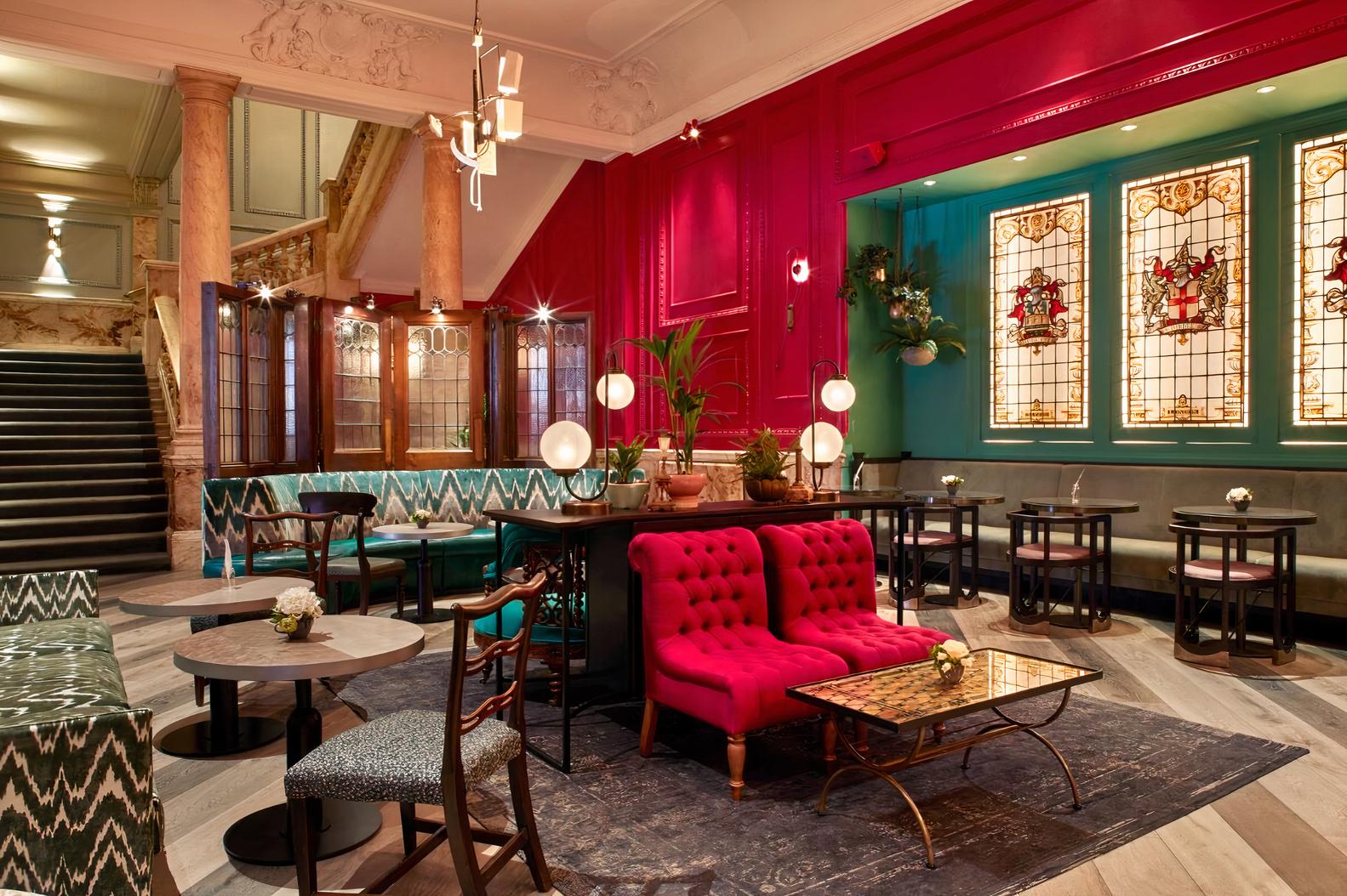 An event space with stained glass windows, velvet seating, and marble pillars at Andaz London Hotel
