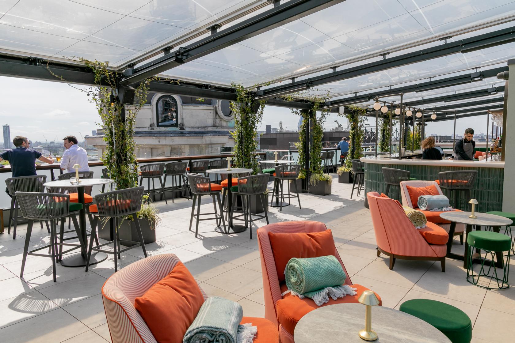A rooftop venue with glass canopy, greenery-covered pillars, and lounge seating at Wagtail.