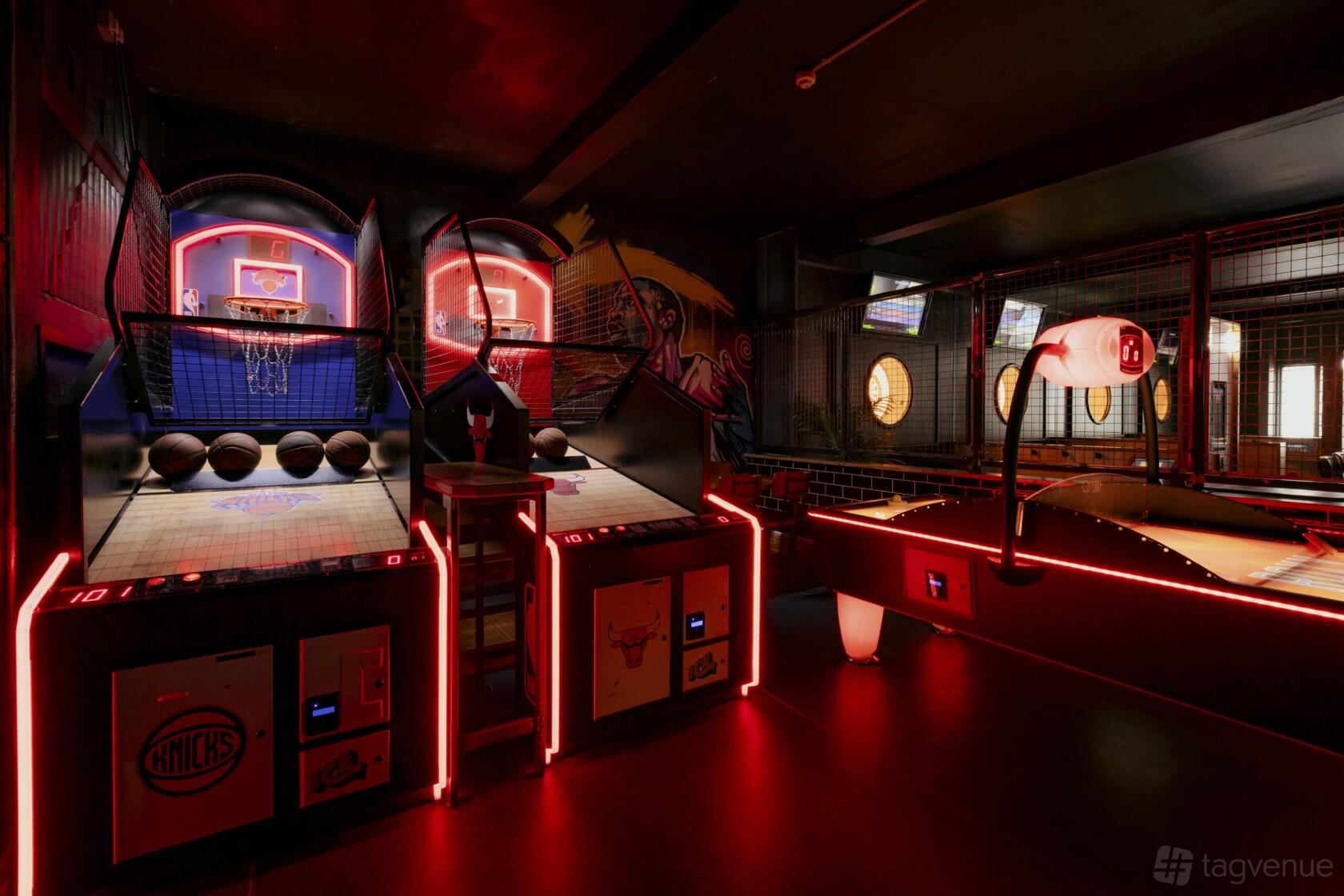A bar with arcade basketball games, neon lighting, and wall murals at Roxy Ball Room Leeds Boar Lane.