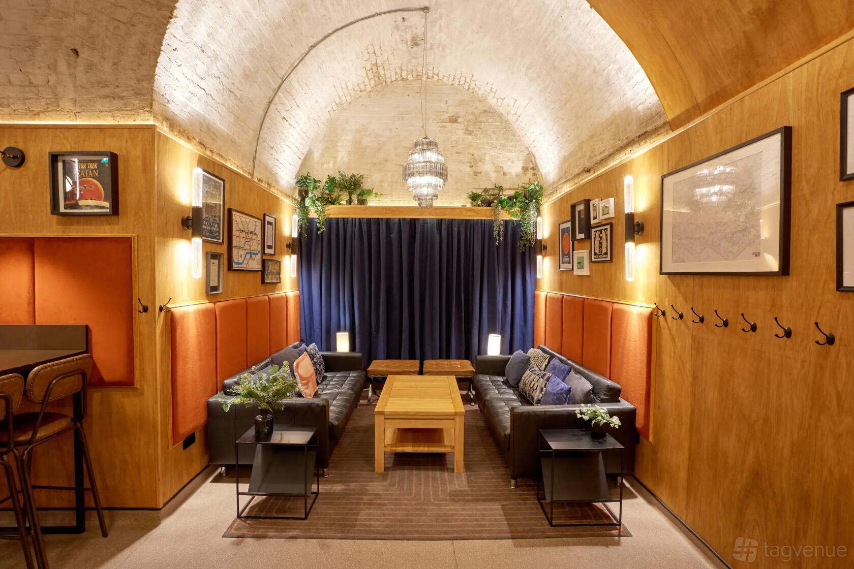 An event space in a pub with an arched brick ceiling, framed artwork, and sofas around wooden tables at Draughts Waterloo.