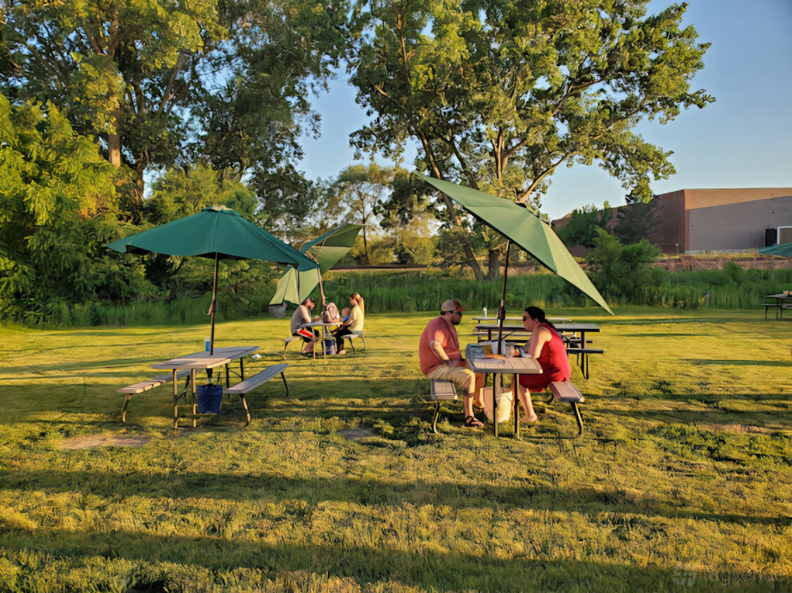 An outdoor brewery lawn with picnic tables and large green umbrellas at Church Street Brewing Company.