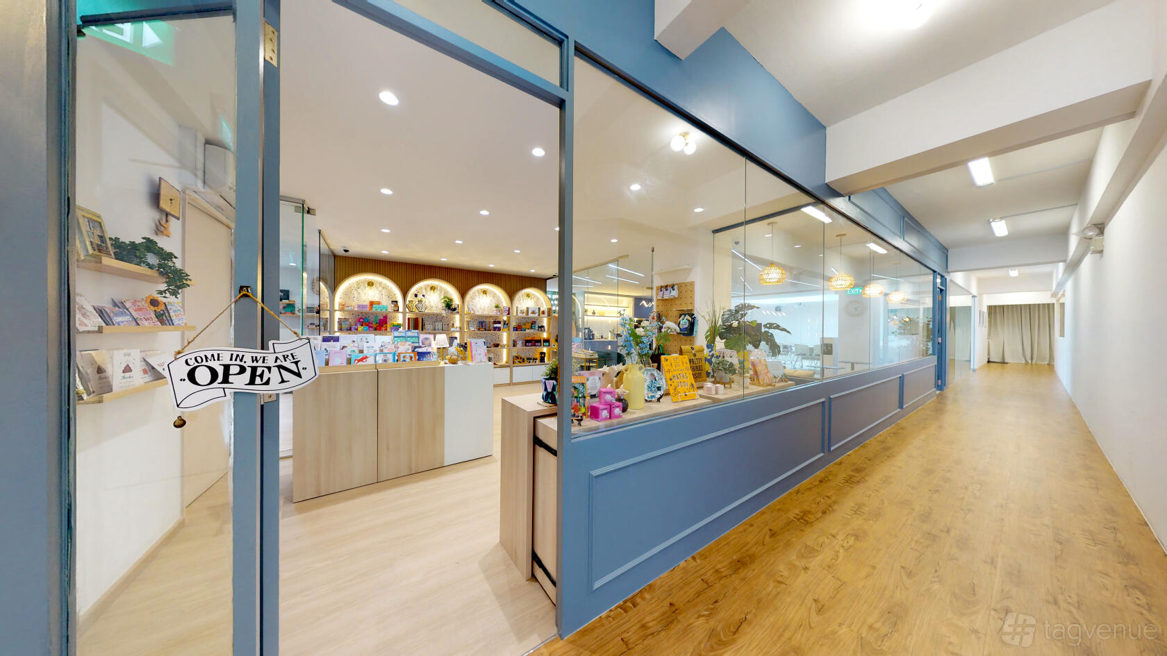 A versatile event space with floor-to-ceiling glass walls, wood flooring, and shelves of merchandise at Wings of the Dawn.