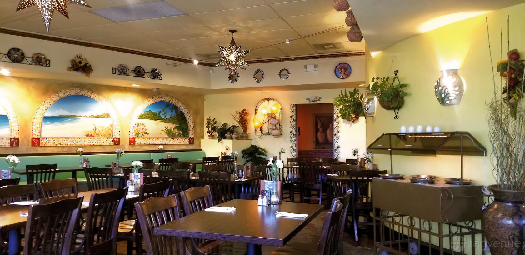 An event space in a restaurant with painted murals, wooden tables and chairs, and hanging star lights at Margaritas Mexican Grill.