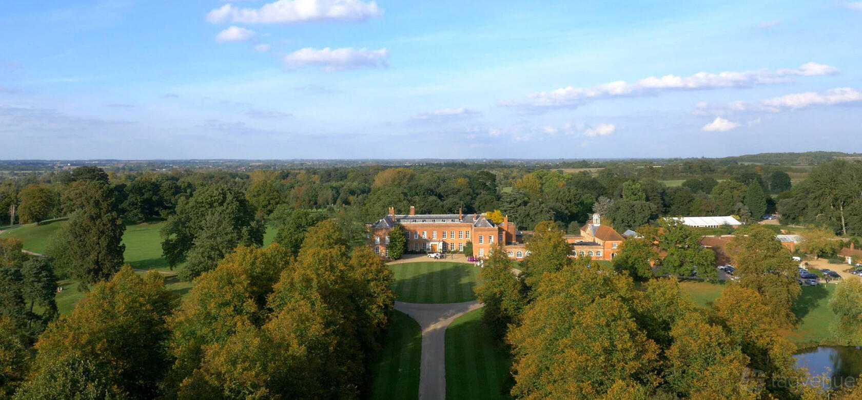 A stately venue with a long tree-lined driveway, expansive manicured lawns, and a historic brick mansion at Braxted Park.