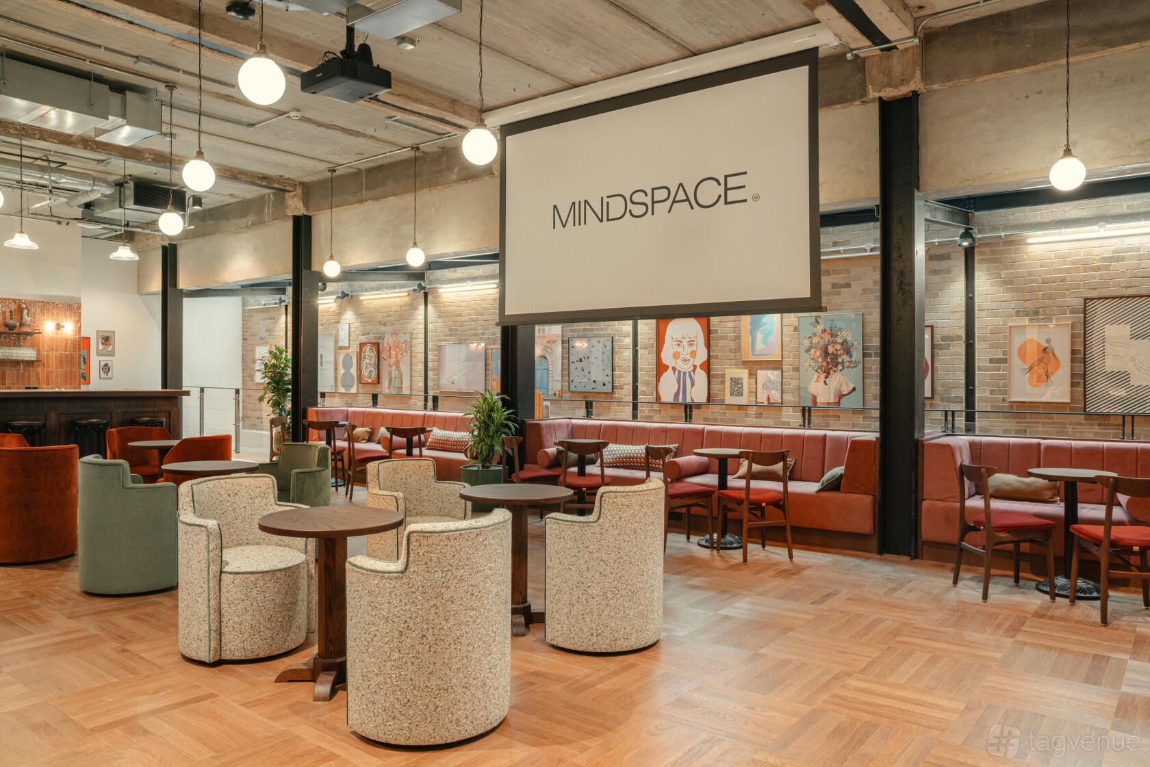 An event venue with wooden floors, modern lounge chairs, and art-covered brick walls at Mindspace - Old Street.