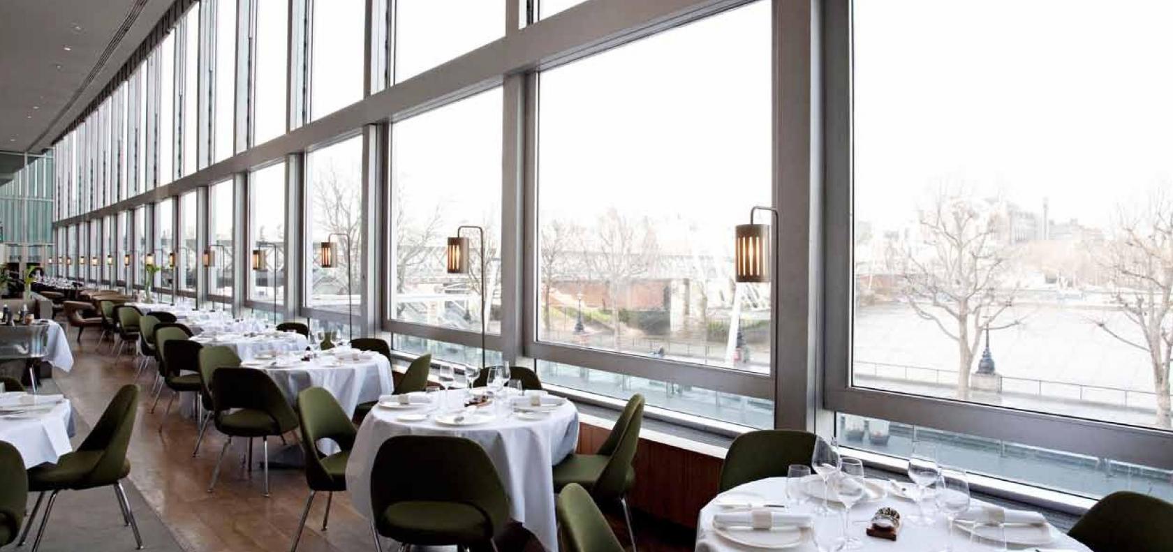 A restaurant with floor-to-ceiling windows, white tablecloths, and river views at Skylon.
