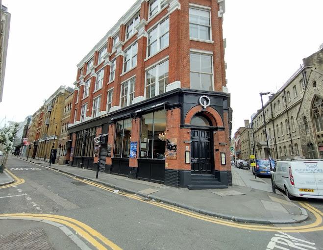 A red-brick corner nightclub with large windows and a black trimmed entrance at Q Shoreditch.