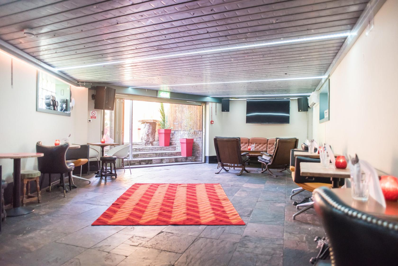 An open event space with slate flooring, eclectic seating, and natural light from sliding doors at Pub on the Park.