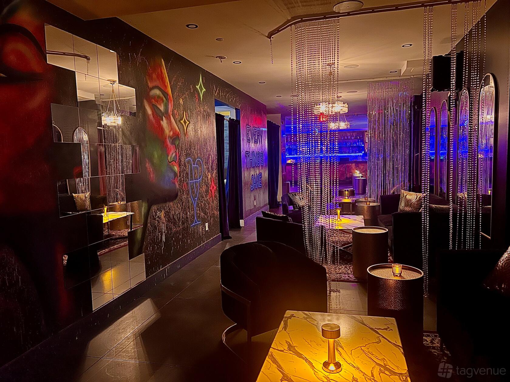 An event space with colorful wall murals, mirrored panels, lounge seating, and hanging bead curtains at Everything's Jake.