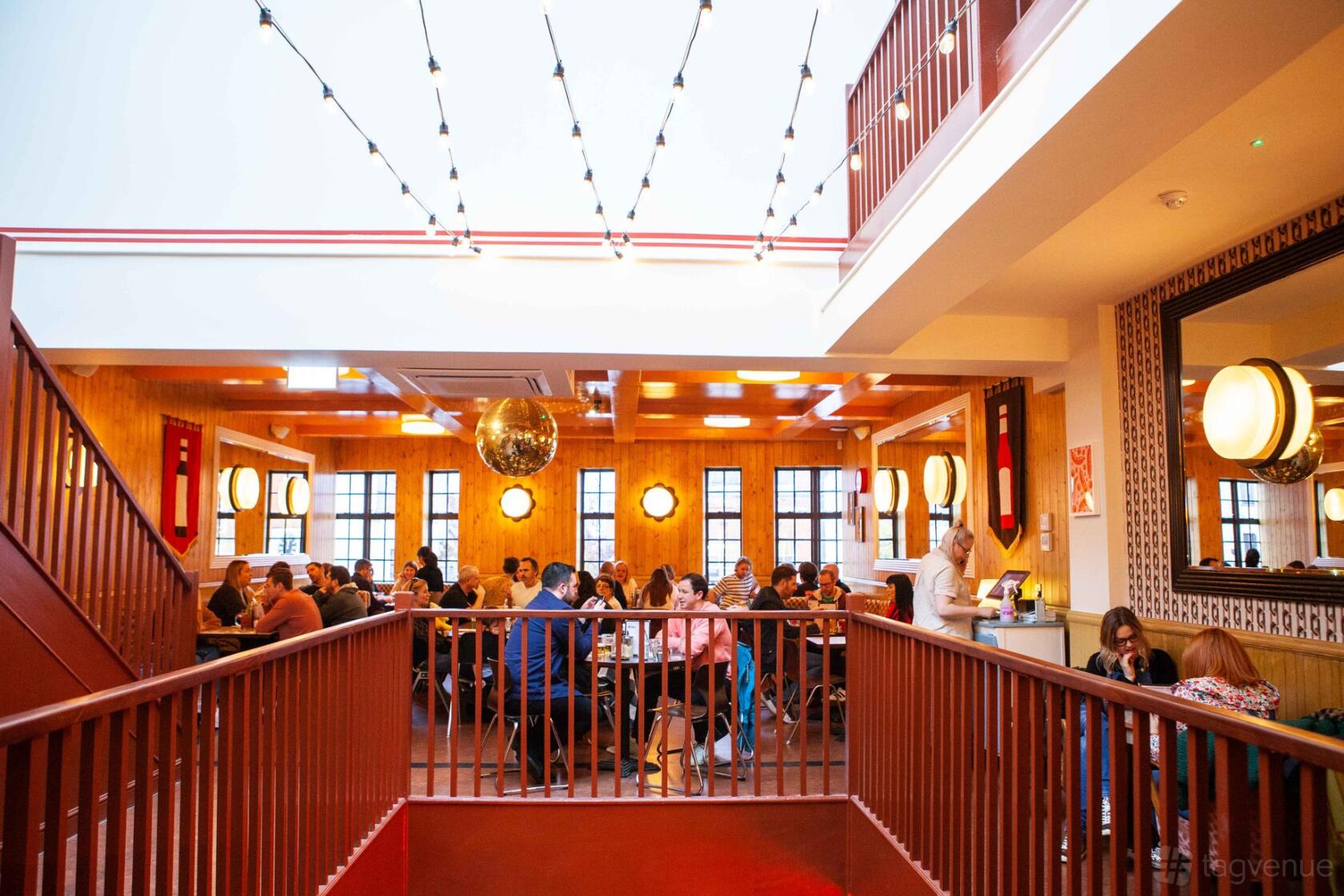 A restaurant dining area with wood-paneled walls, string lights, and a mirrored disco ball at The Breakfast Club Chelmsford.