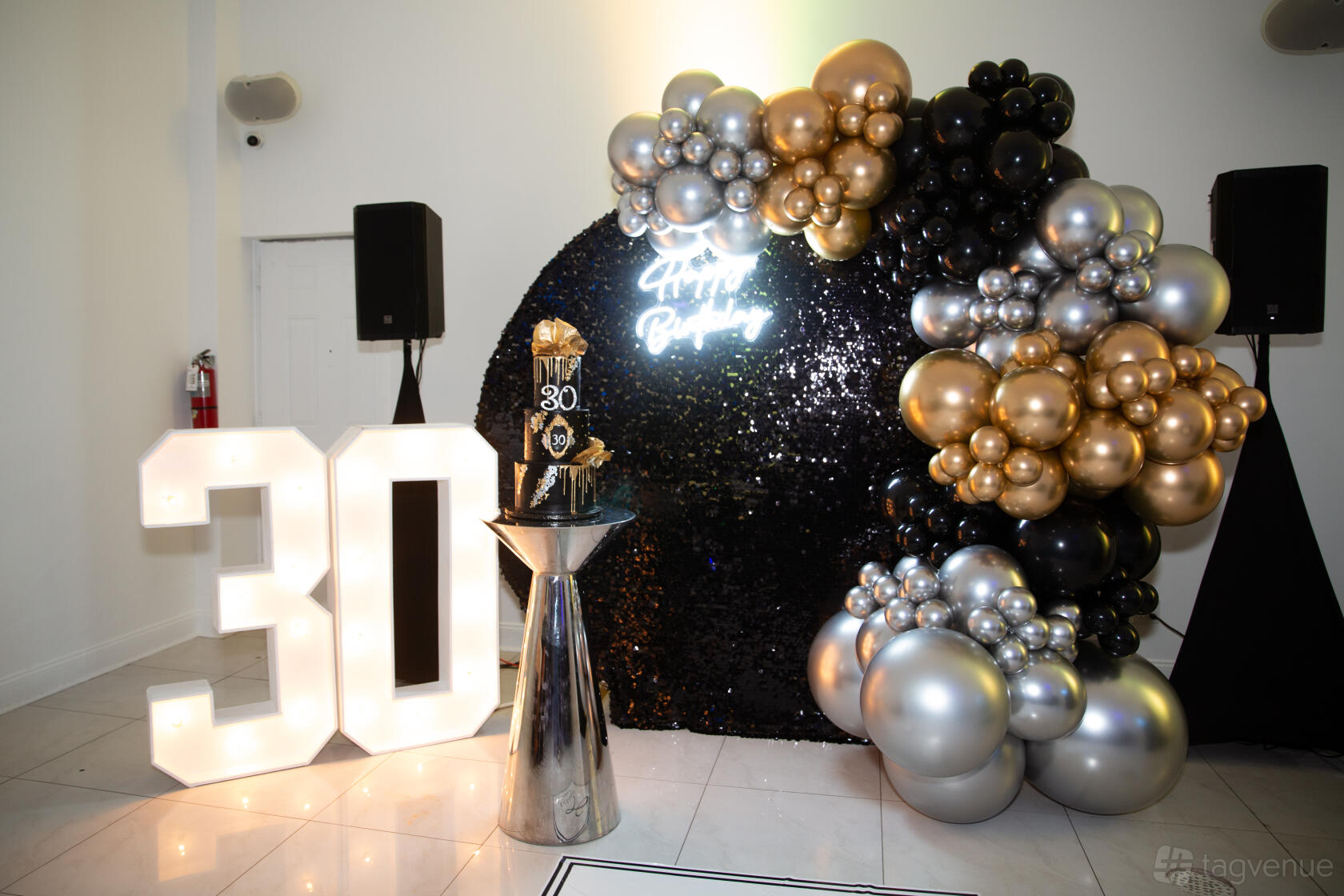 A function room with a black sequin backdrop, illuminated 30 sign, and metallic balloon display at Prime143.