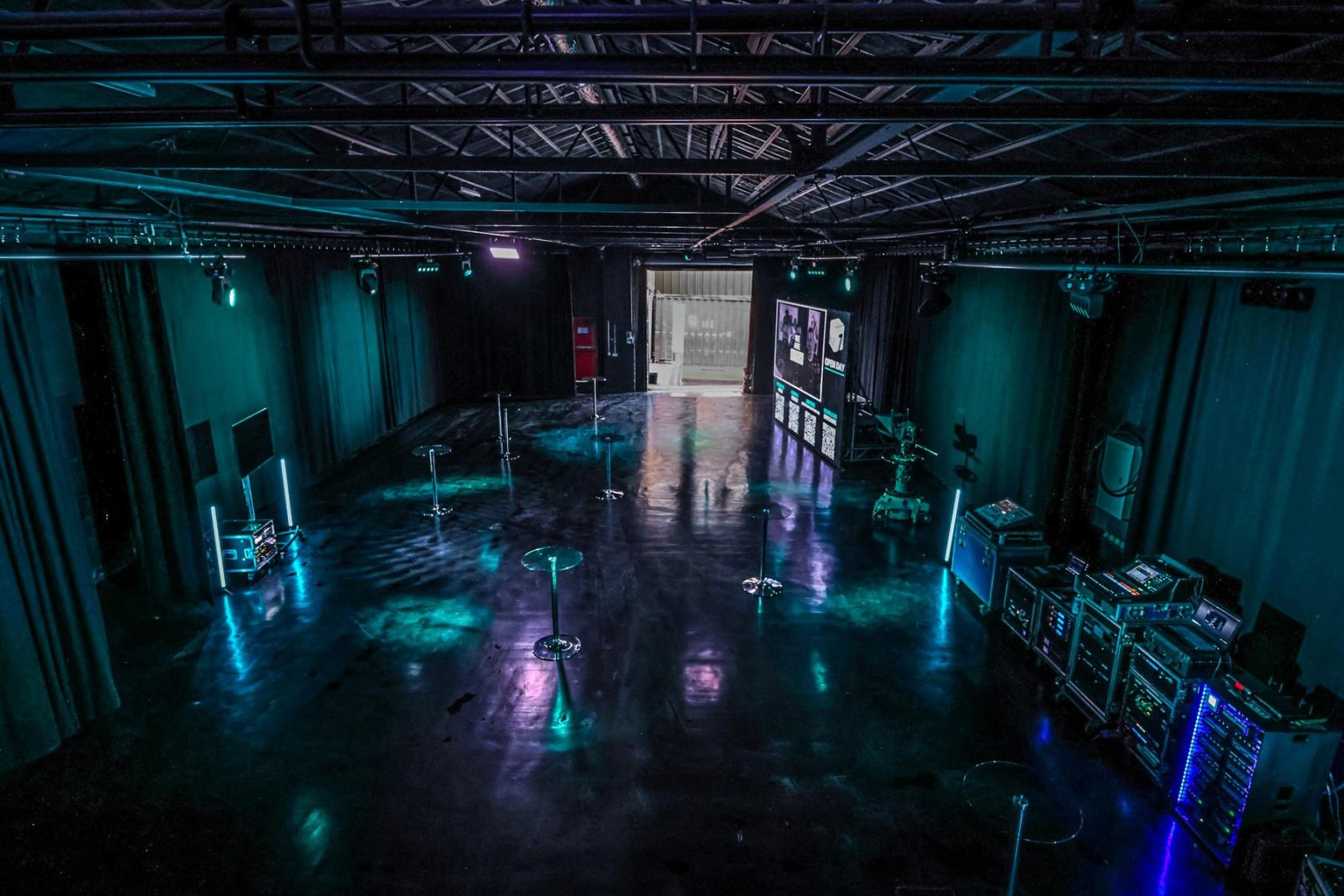 A spacious film studio with polished floors, stage lighting, and sound equipment racks at Box 7 Studio.