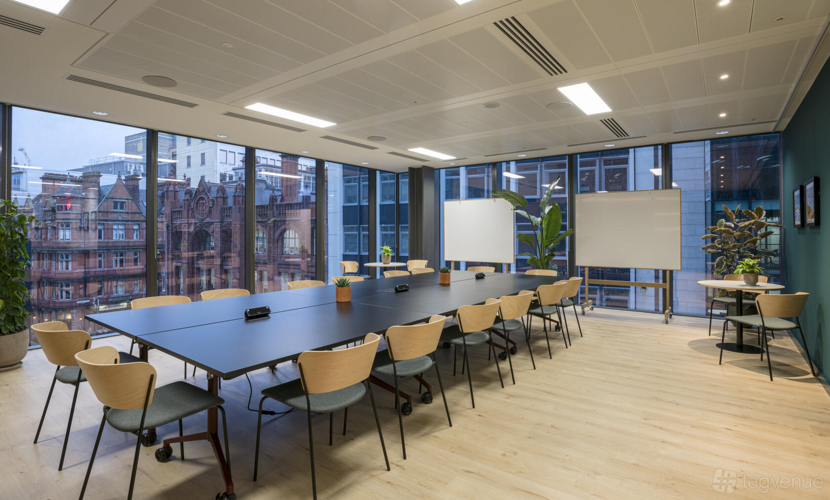 An event room with floor-to-ceiling windows, a long conference table, and wooden chairs at Eighteen.