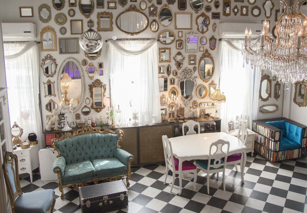 An event venue with vintage furniture, wall of ornate mirrors, chandeliers, and checkered floors at The Love Shack.