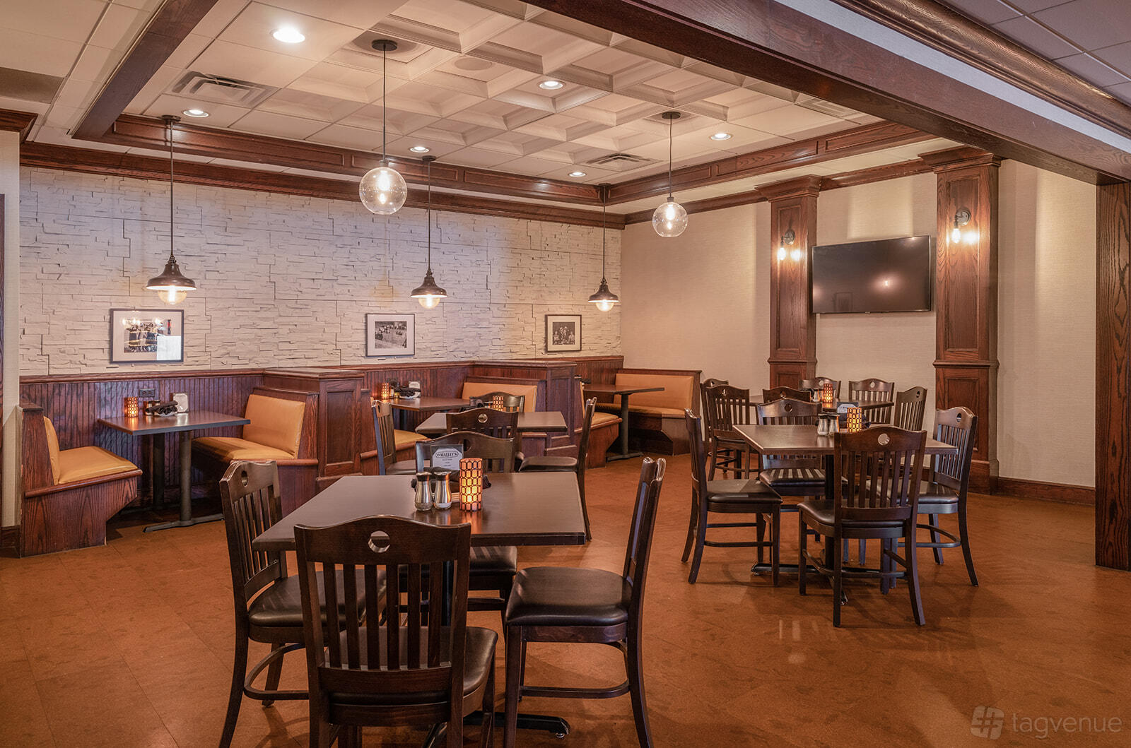 A pub with wood-paneled walls, pendant lighting, booth seating, and framed photos at O'Malley's Pub.