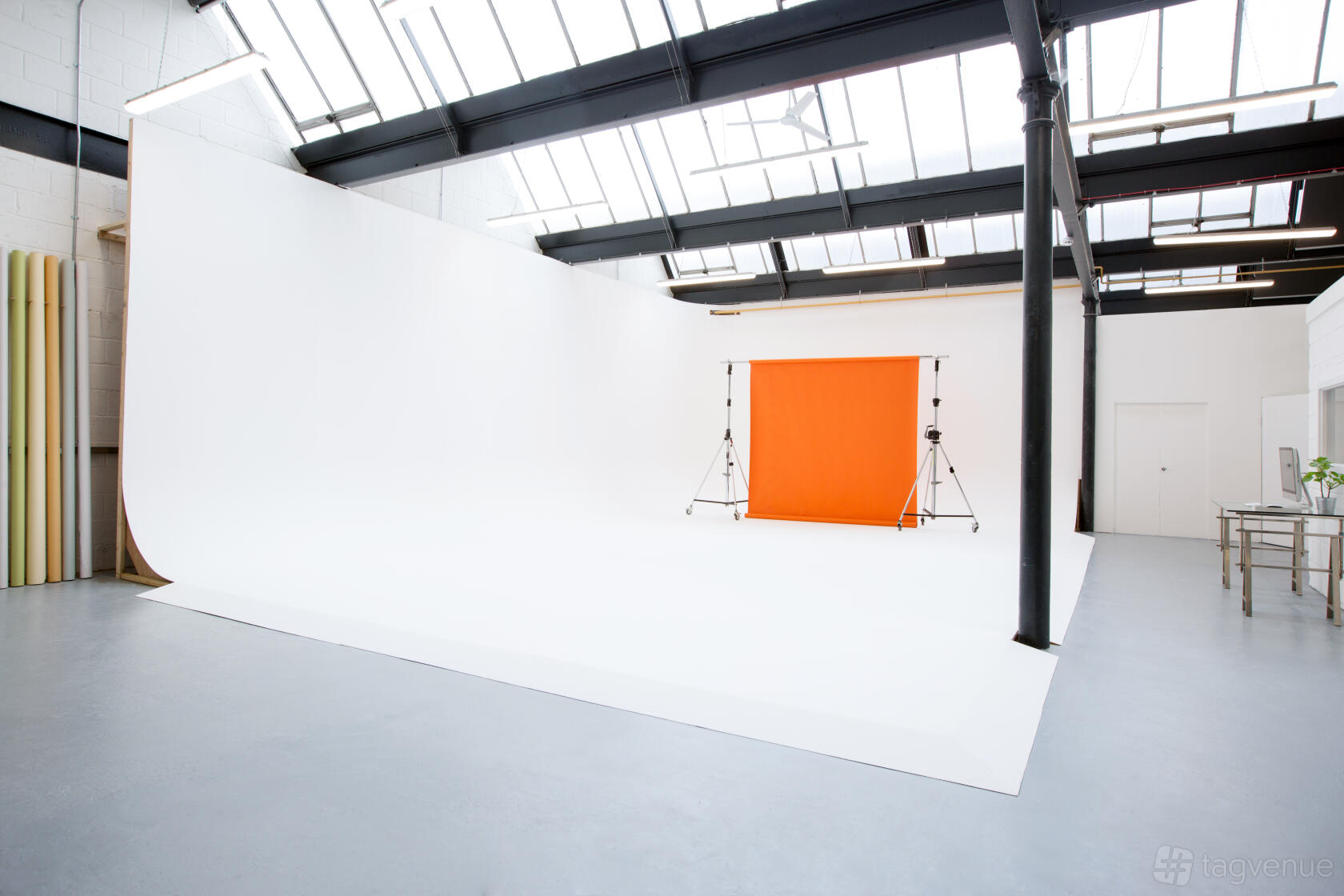 A photo studio with a large white infinity cove, skylights, and an orange backdrop at Myrtle Studios.
