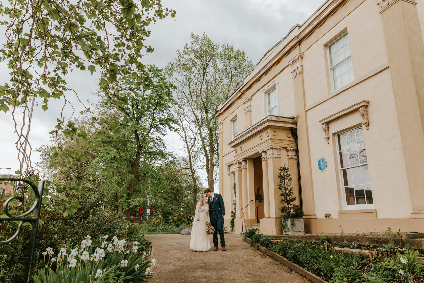 A historic building with a columned entrance and landscaped garden at Elizabeth Gaskell's House.