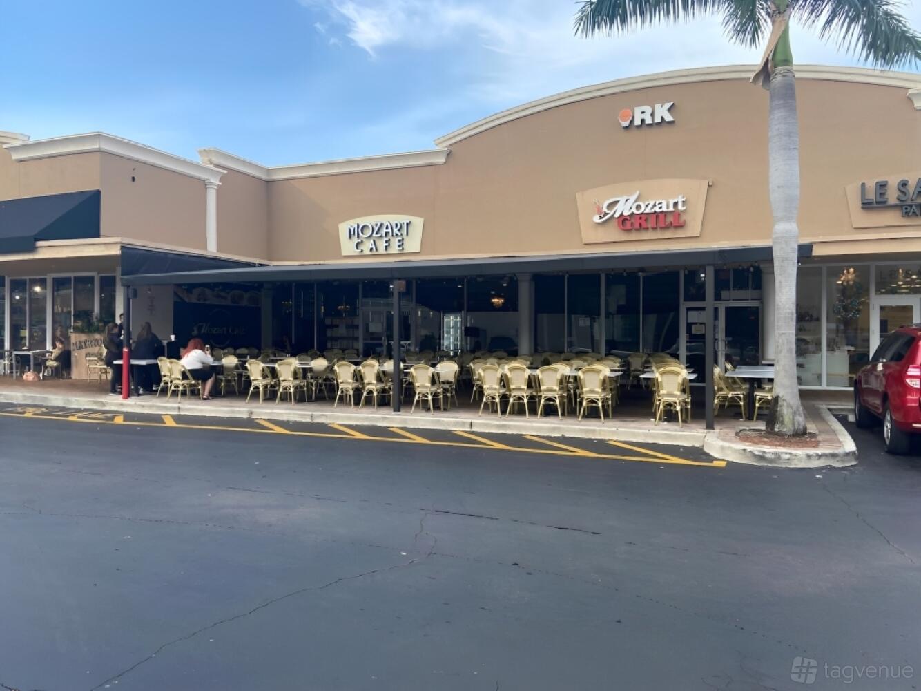 A restaurant with outdoor seating under a covered patio and rows of bistro chairs at Mozart Cafe.
