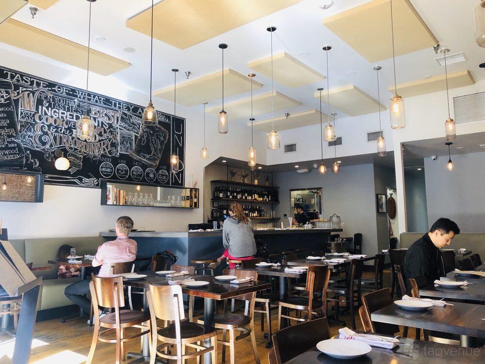 A restaurant dining area with hanging pendant lights, a chalkboard wall mural, and wooden tables at Union Restaurant.