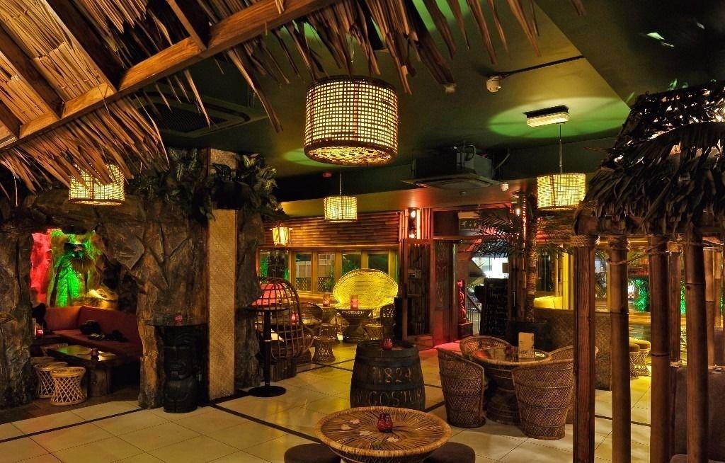 An event space in a cocktail bar with wicker furniture, bamboo decor, and rattan pendant lights at Sugar Cane.