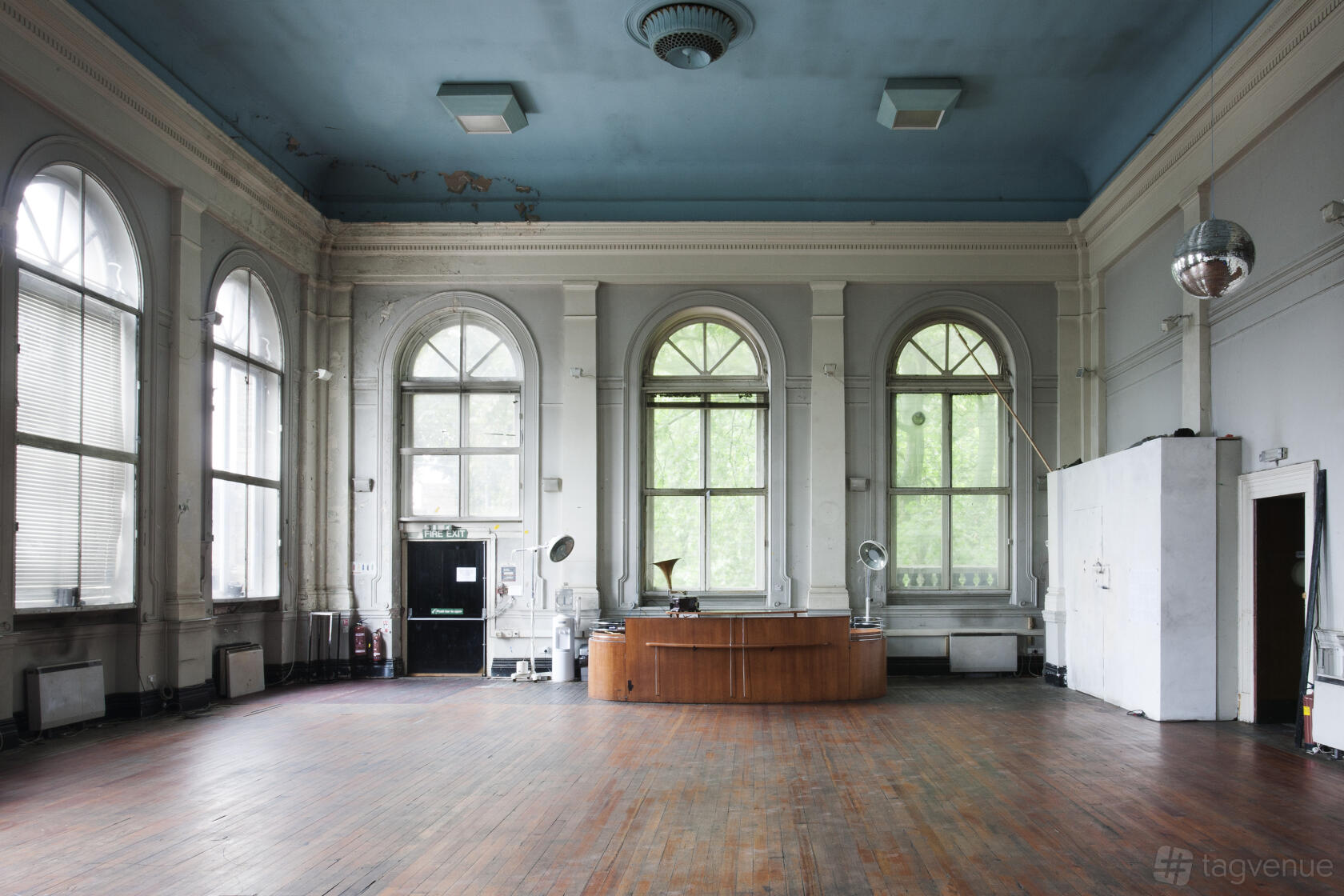 A hall with tall arched windows, a high blue ceiling, and wooden floors at Limehouse Town Hall.