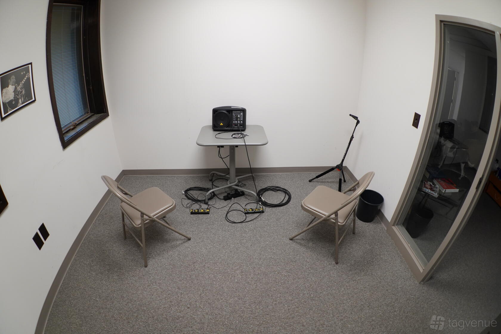 A rehearsal room with two folding chairs, a small table with an amplifier, and cables at Rehearse Live.