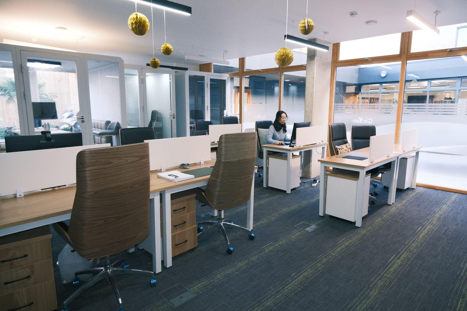 A coworking space with shared desks, high-backed chairs, and large windows at Unit 5.