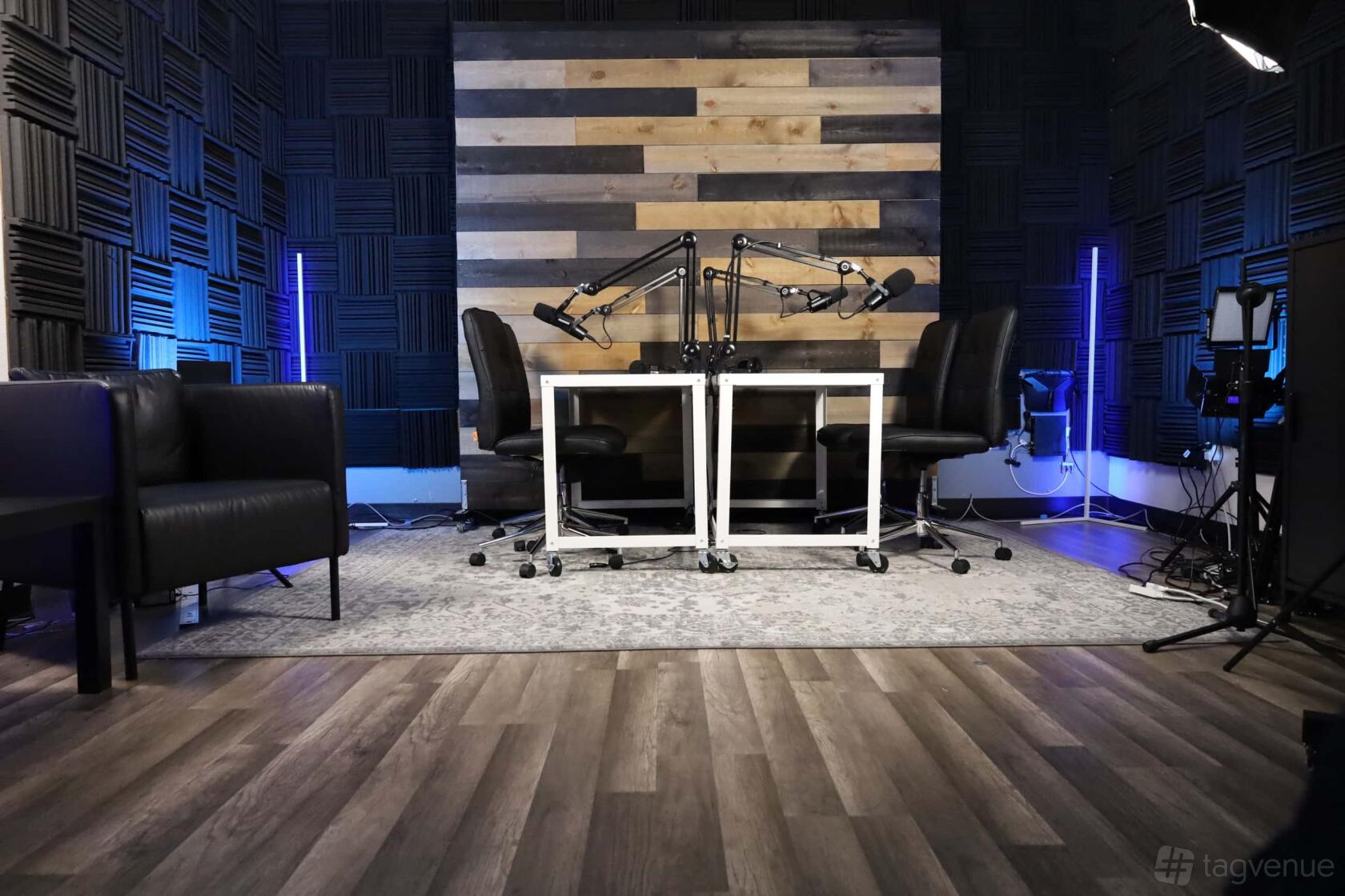 A recording studio with soundproof foam walls, two microphones on adjustable arms, and lounge chairs at SCVStudios.