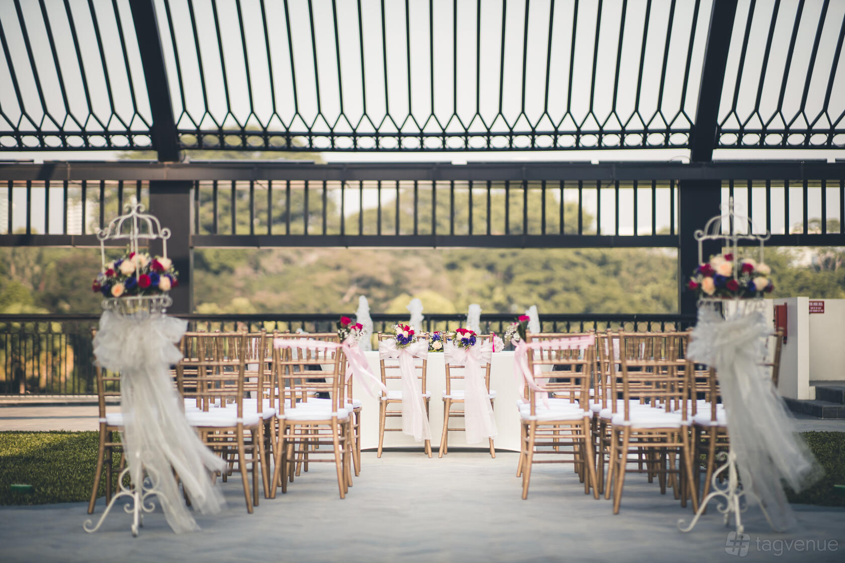 A rooftop event space with wooden chairs, floral arrangements, and an open metal canopy at Grand Park City Hall.
