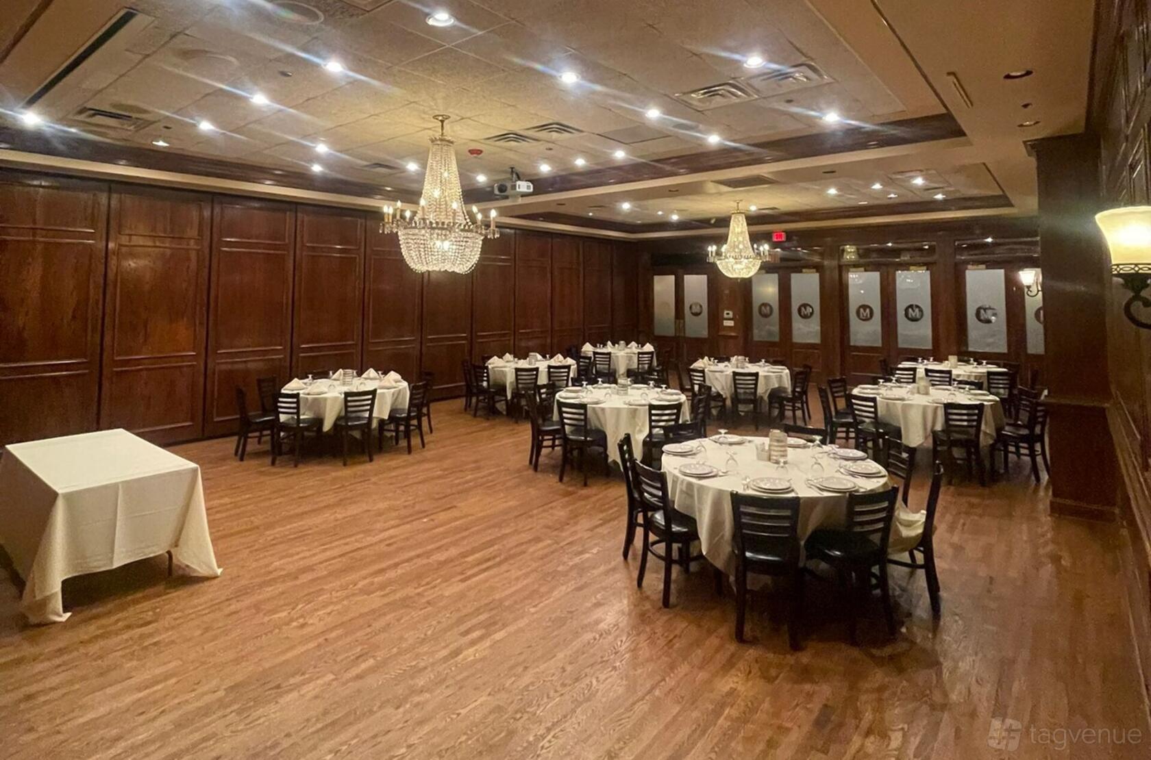 A restaurant ballroom with wood-paneled walls, chandeliers, and round tables with white linens at Maggiano's Little Italy Chevy Chase.