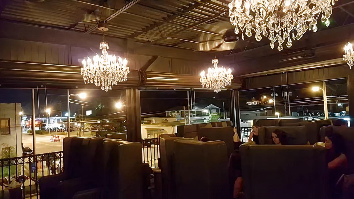 A terrace cocktail bar with crystal chandeliers and high-backed booths at The Marble Ring.
