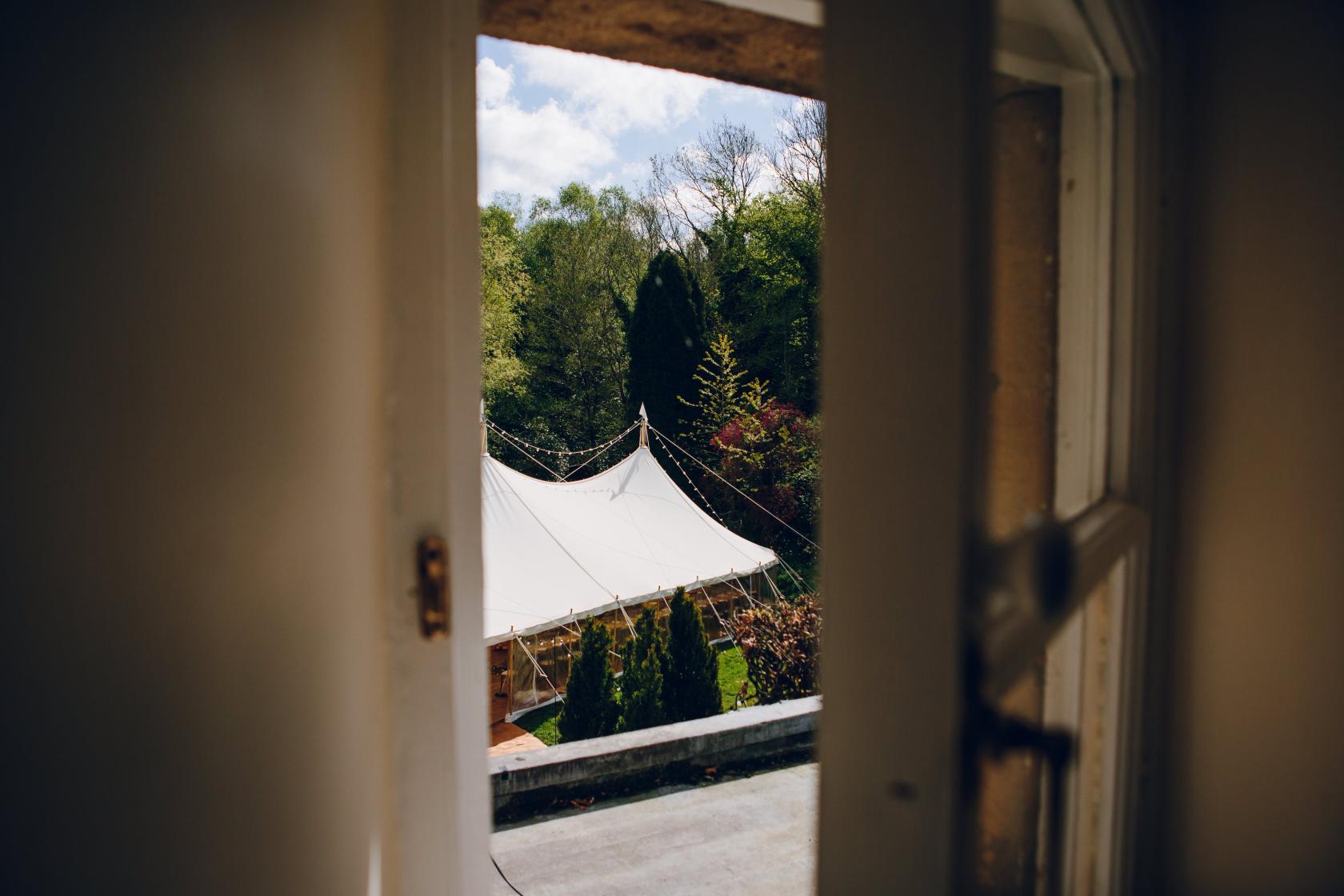 A country house garden with a white event marquee surrounded by trees at Heathy Lea.
