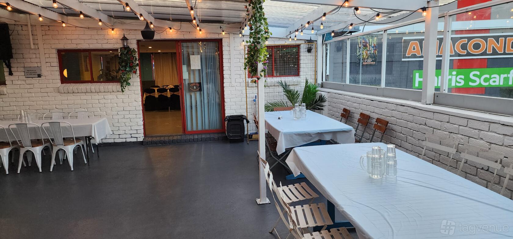 A rooftop restaurant with white brick walls, string lights, covered seating, and potted plants at Third Eye Bar Rooftop Restaurant.