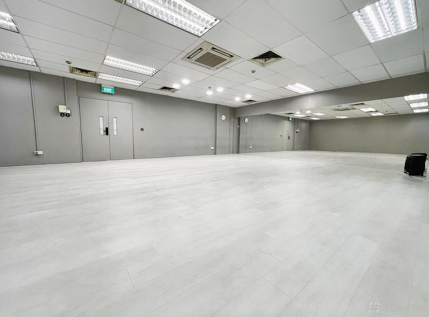 A dance studio with light wood floors, mirrored wall, and ceiling lights at Tokki Studio.