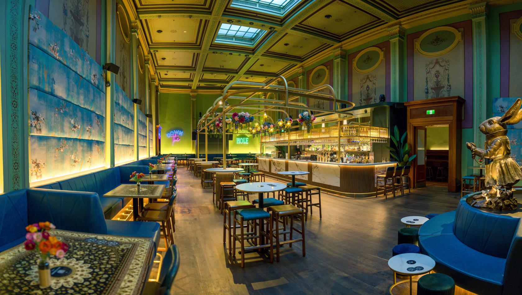 A hotel bar with a long marble bar counter, high ceilings with skylights, and wall murals at The ArtHouse Hotel.