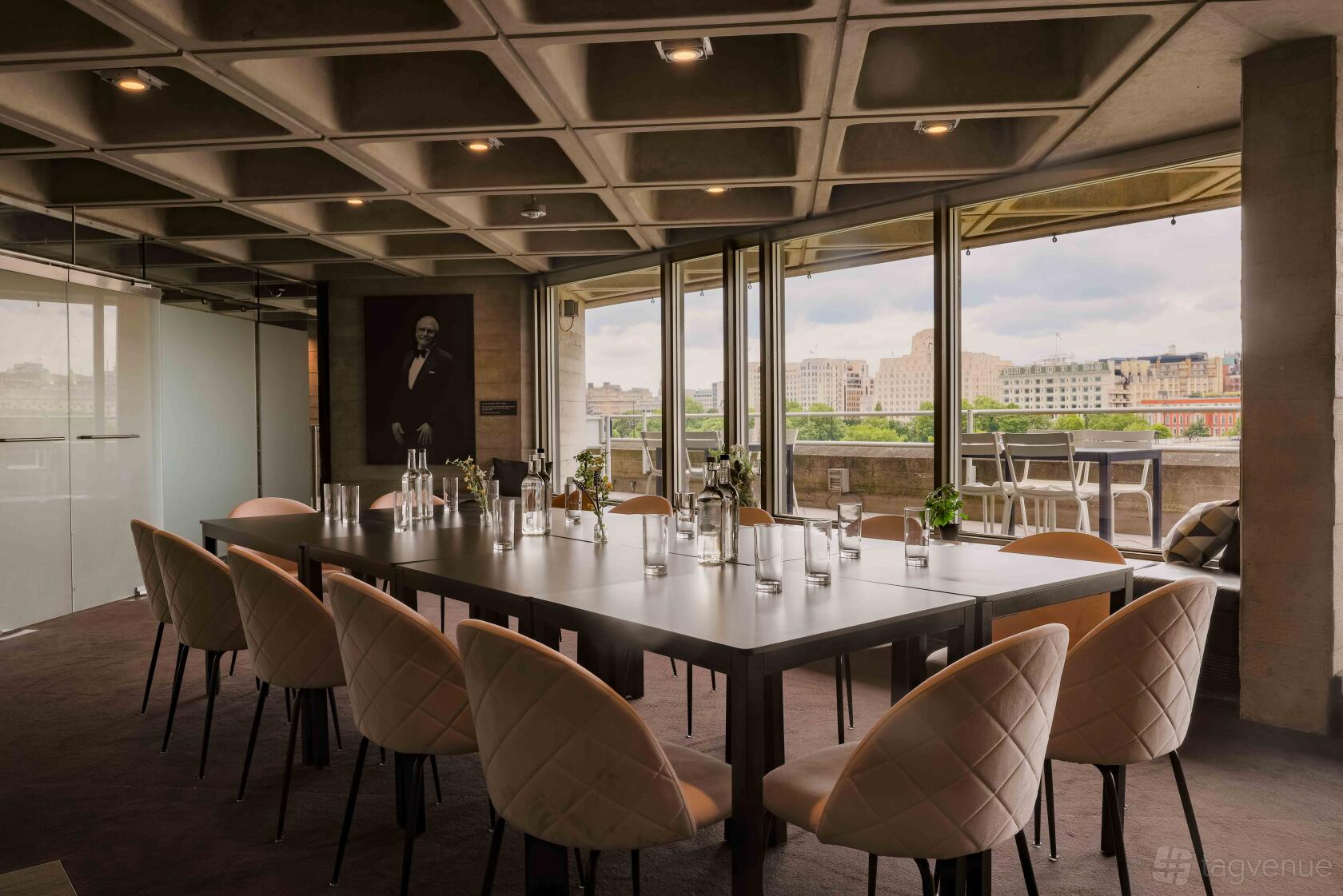 A meeting room with a long table, modern chairs, floor-to-ceiling windows, and city views at The National Theatre.