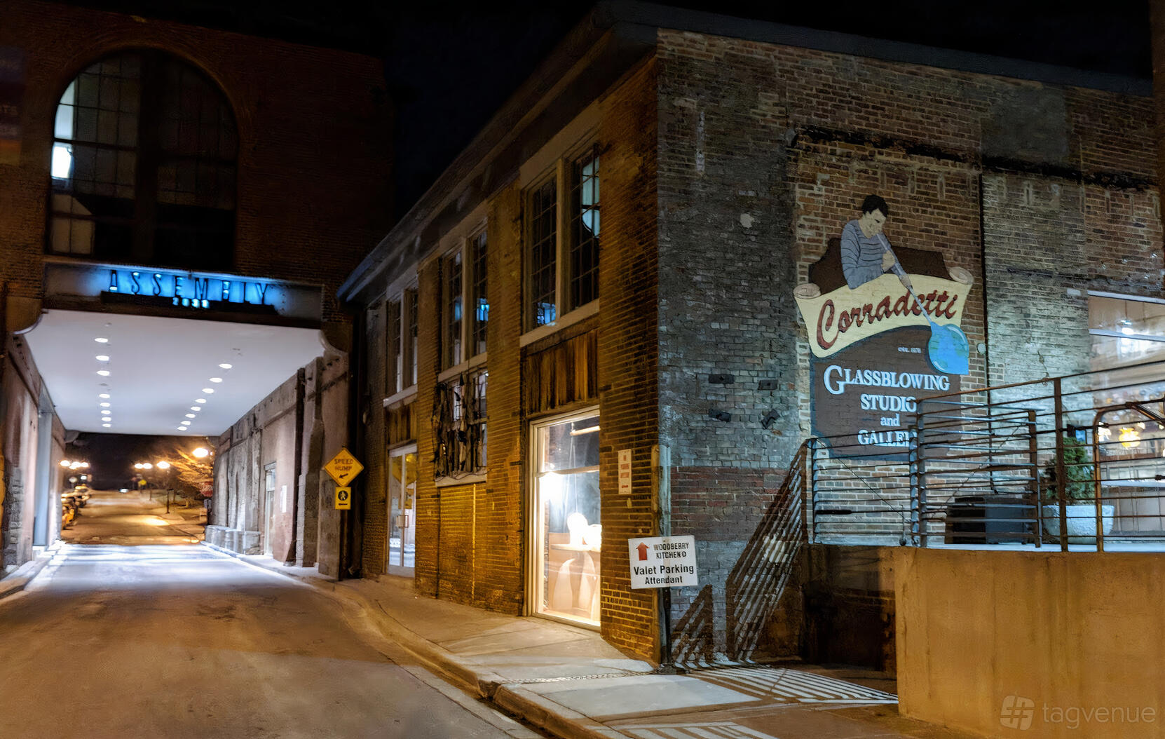 A brick gallery building with large windows and a painted mural sign at Corradetti Glass Studio.