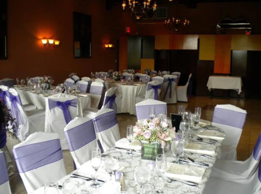 A hall terrace with round tables draped in white linens and chairs wrapped with lavender sashes at The Douglaston Manor.