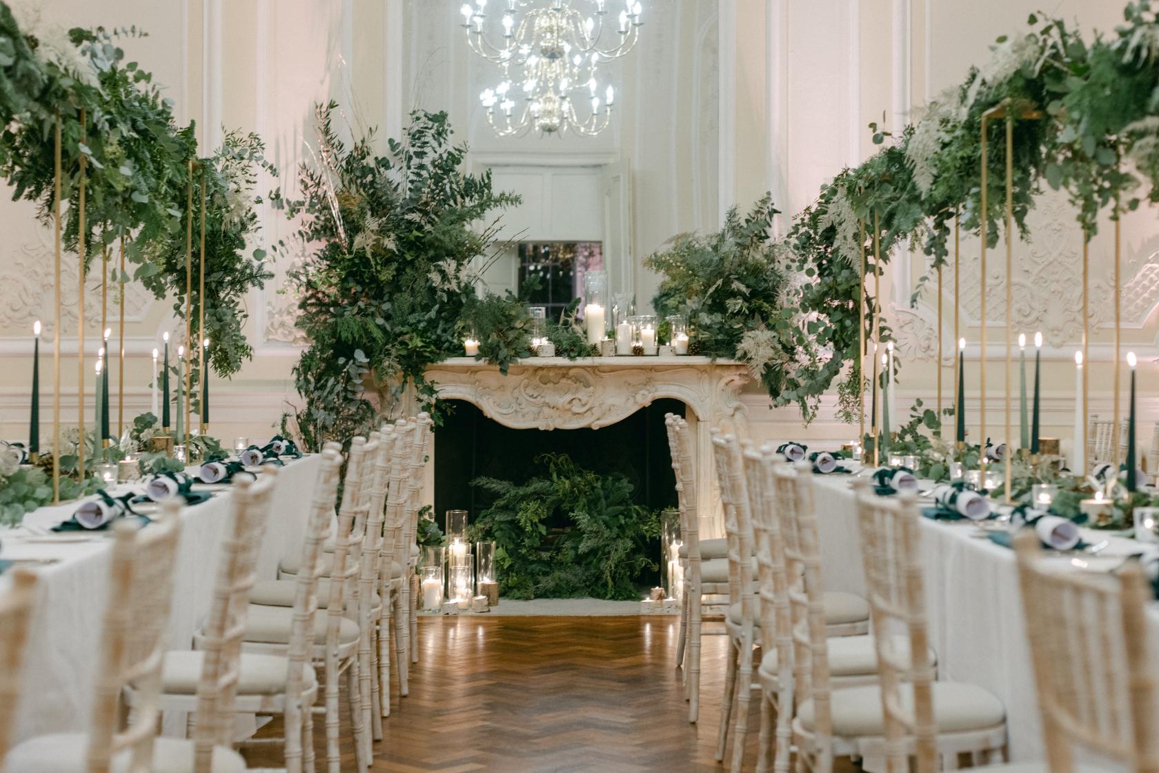 A function room with long banquet tables, white linens, and abundant greenery at {10-11} Carlton House Terrace.