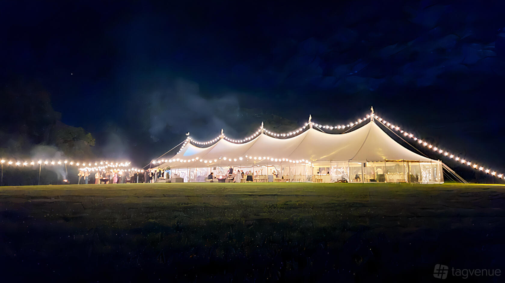An event venue with a large marquee tent, illuminated by string lights on a grassy lawn at Peacock and Bow.