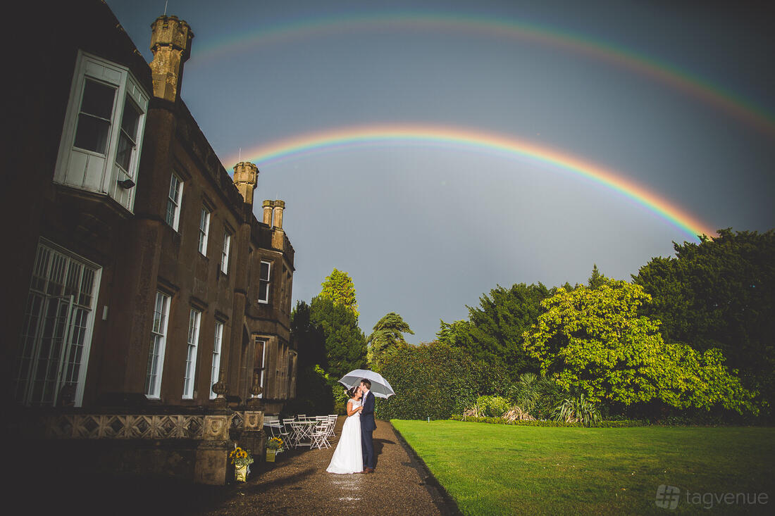 An event venue with a historic mansion facade, lush lawn, and double rainbow at Nonsuch Mansion.