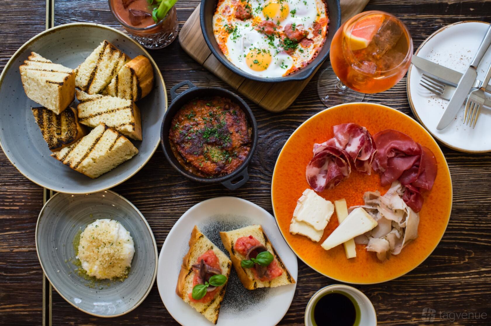 A dining room table with assorted brunch dishes, cured meats, cheeses, and toasted bread at The Ampersand Hotel.