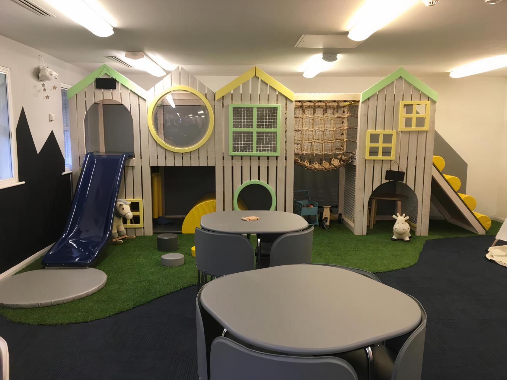An event venue with a whimsical indoor playground, slides, playhouses, and round tables at Tiny Boo.