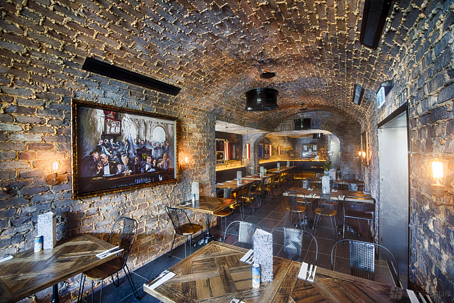 A dining room with arched exposed brick ceilings, wood tables, and wall sconces at Criniti's Carlton.