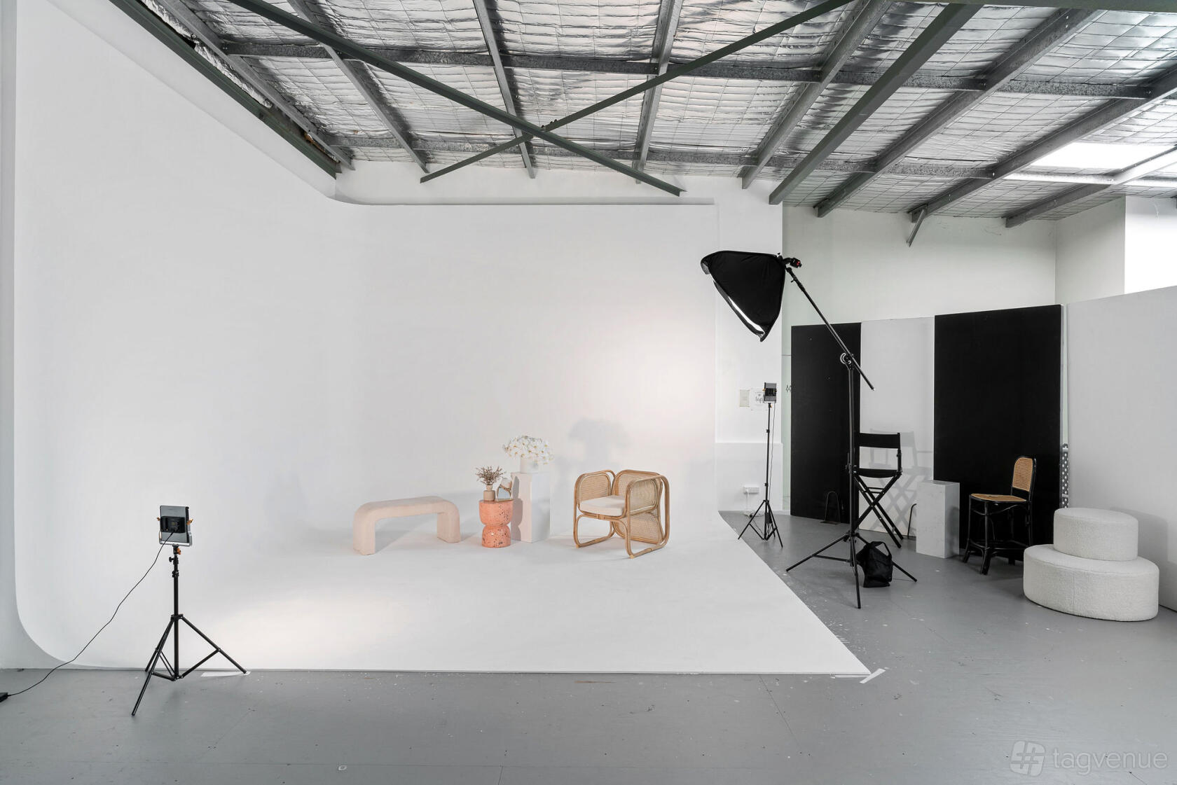 A warehouse photo studio with a large white cyclorama wall, exposed ceiling beams, and studio lighting at The Studio Event Space.