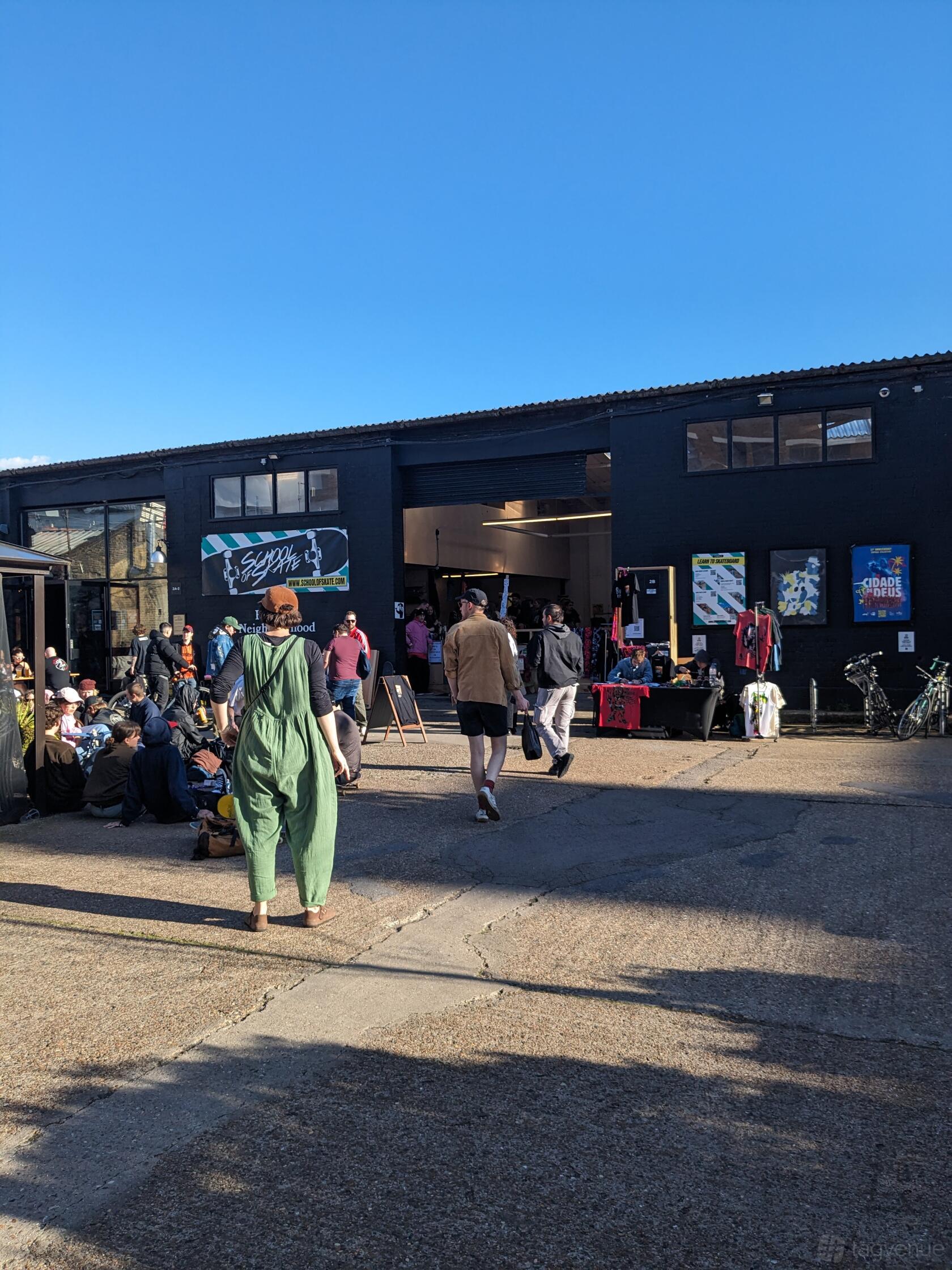 An open sports hall exterior with a black facade, tall windows, and people gathered outside at School of Skate Copeland Park.